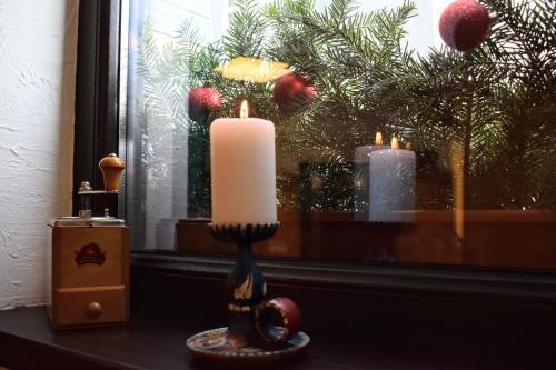 a candle on a window sill with a christmas tree at Vila Seva in Vatra Dornei