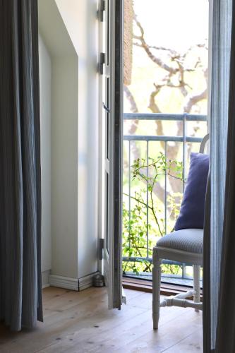 a room with a chair and a balcony with a window at Bakkehuset Countryhouse in Skovby
