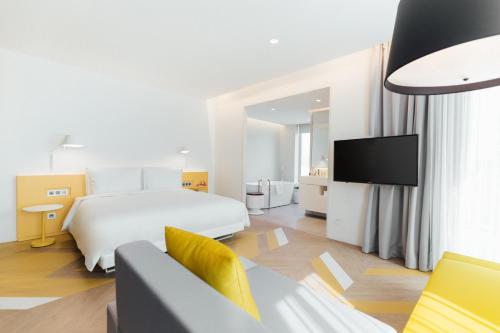 a white hotel room with a bed and a tv at The Place Taipei in Taipei