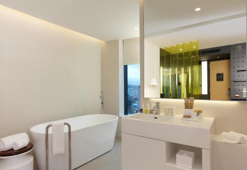 a white bathroom with a tub and a sink at The Place Taipei in Taipei