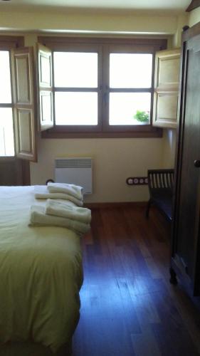 um quarto com uma cama, janelas e uma cadeira em La Forna del Coto em Coto de Buenamadre