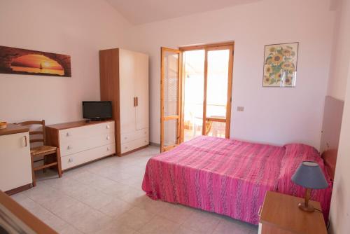 ein Schlafzimmer mit einem rosa Bett und einem TV in der Unterkunft Case Vacanza Renella 3 beds: Balcony, wifi, self-catering, 200mt from the sea in Sciacca