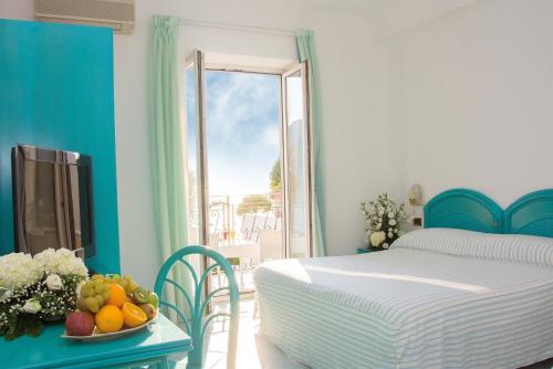 1 dormitorio con 1 cama y una bandeja de fruta en la mesa en Hotel Capizzo en Ischia