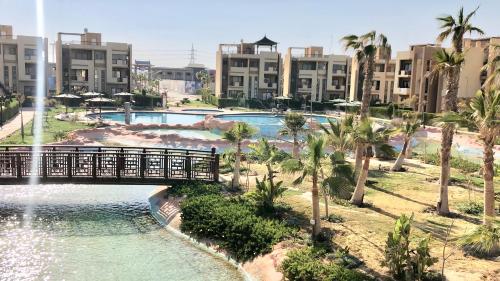 a bridge over a pool with palm trees and buildings at Chalet in Bluebay Asia Resort Ain Sokhna in Ain Sokhna