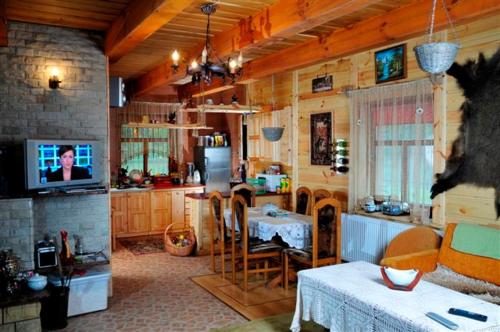 a living room with a tv and a kitchen with a table at Gajówka Sajczyce - gospodarstwo agroturystyczne in Chełm