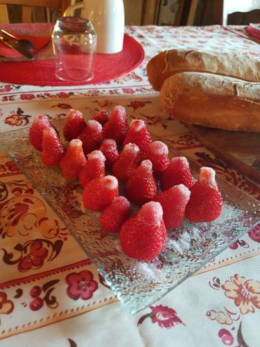 a plate of strawberries on a table with bread at La Terrasse de Peyre in Comprégnac
