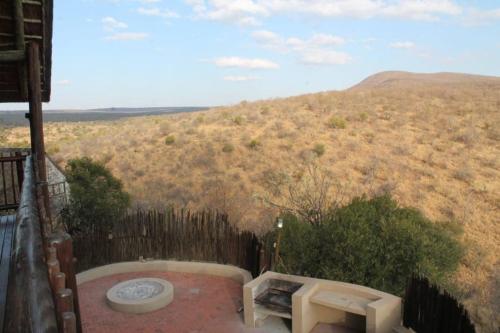 a balcony with a bench and a view of a hill at Kanaan, Mabalingwe in Mabula