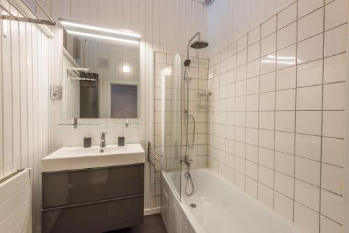 uma casa de banho branca com um lavatório, uma banheira e um chuveiro em Le Gîte de Catherine em Esneux