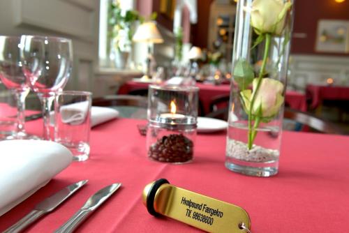 a table with a red table cloth with a candle and flowers at Hvalpsund Færgekro in Hvalpsund