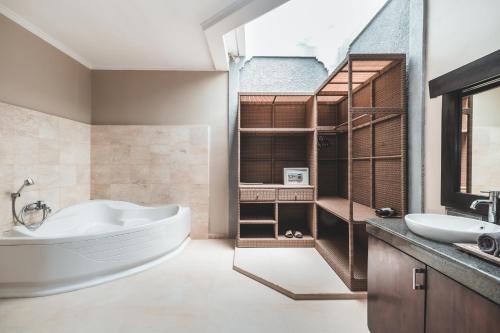 a bathroom with a large tub and a sink at Dura Villas Bali at Kerobokan in Kerobokan
