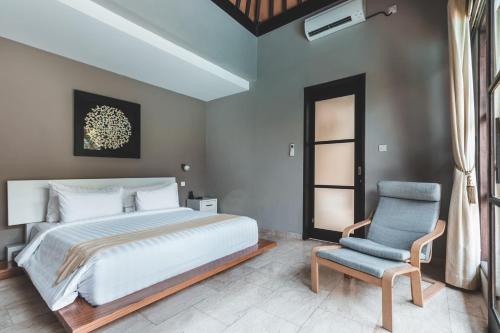 a bedroom with a large bed and a chair at Dura Villas Bali at Kerobokan in Kerobokan