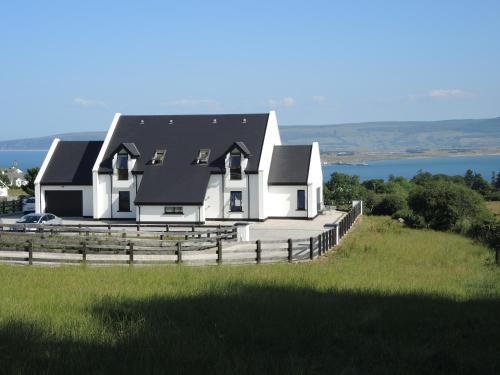 a white house with a black roof on top of a hill at On the Rocks B&B in Greencastle