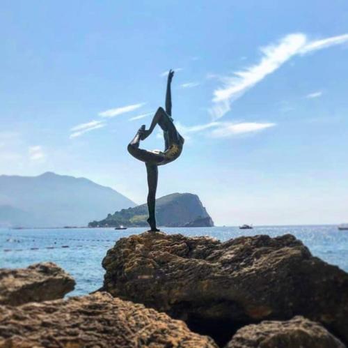 a person doing a pose on a rock on the ocean at Apartments Dragišić in Sveti Stefan