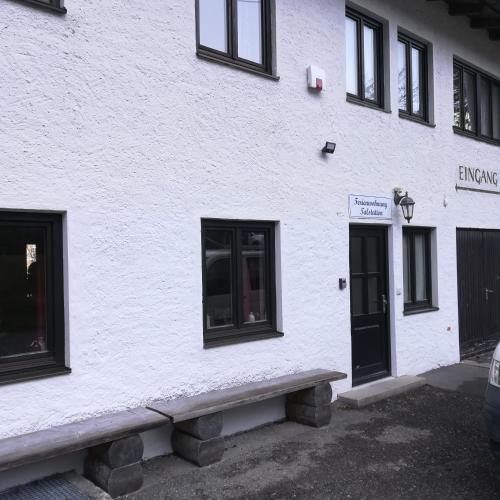 a white building with a bench in front of it at Ferienwohnungen Karwendelbahn in Mittenwald