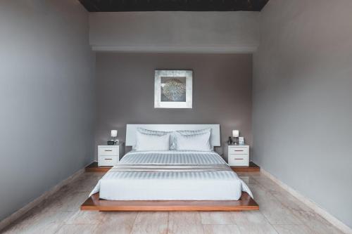 a bedroom with a large white bed with two night stands at Dura Villas Bali at Kerobokan in Kerobokan