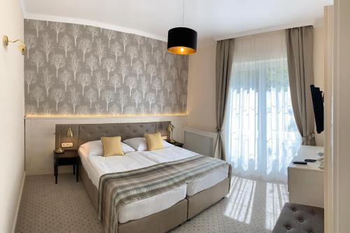 a bedroom with a bed and a large window at Villa Medici Hotel & Restaurant in Veszprém