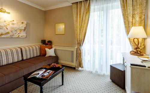 a living room with a couch and a large window at Villa Medici Hotel & Restaurant in Veszprém