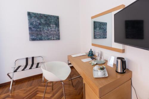 Habitación con escritorio, TV y silla. en Palazzo Filisio - Regia Restaurant en Trani