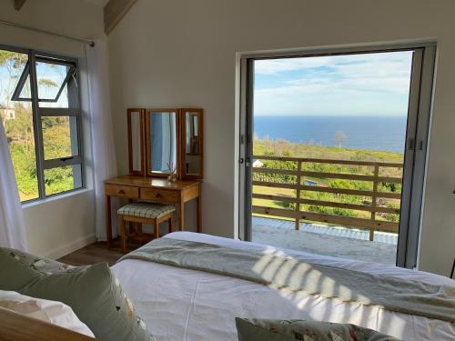 1 dormitorio con cama y vistas al océano en Trinity Farm Ocean view Cottage en Plettenberg Bay