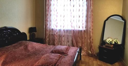 a bedroom with a bed and a mirror and a window at Lenina 7 in Tiraspol