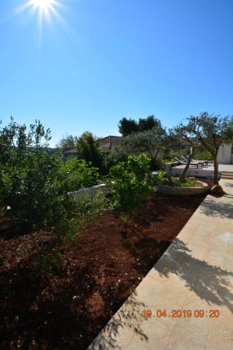 a garden with trees and a sidewalk at Dreamlodge - Luxe Dalmatian Villa, private pool, parking, mooring, breathtaking sea & mountain view, at 150 m from idyllic private beach in Rogač