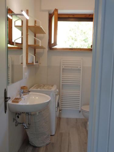 un bagno con lavandino, WC e finestra di La casa di Nina a Quercianella