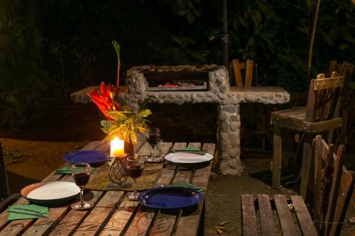 a wooden table with a candle and plates and wine glasses at Hotel Casa Merlin in Puerto Viejo