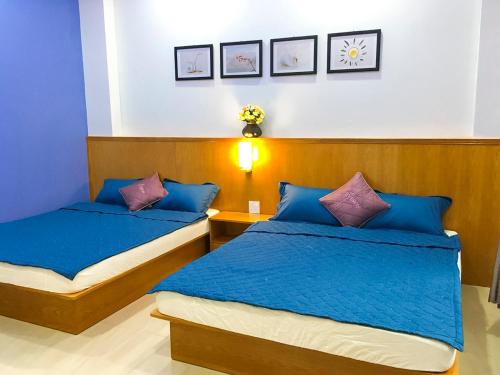 - 2 lits dans une chambre avec des oreillers bleus et violets dans l'établissement 202s Homestay, à Quy Nhơn