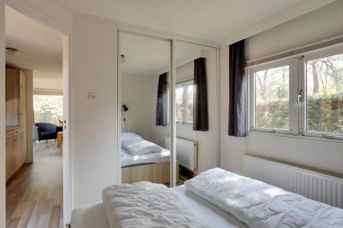 a bedroom with two beds and a mirror at Bungalowpark Het Verscholen Dorp in Harderwijk