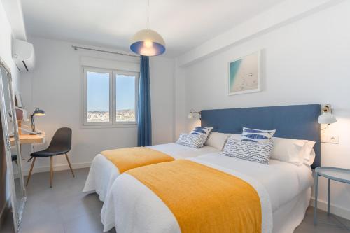 um quarto branco e azul com uma cama e uma secretária em iloftmalaga San Millán em Málaga