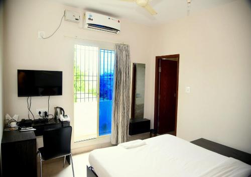 a bedroom with a bed and a desk and a window at Orange Corner, Near Kempegowda Airport, Airport Pickup And Drop Available 24x7 in Bengaluru