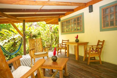 a porch with wooden chairs and tables and a table at Hotel Casa Merlin in Puerto Viejo