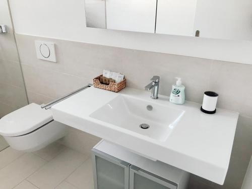 a white bathroom with a sink and a toilet at Easy-Living Apartments Dietwil in Dietwil