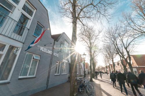 a group of people walking down a street next to a building at Het Vlielandhotel in Oost-Vlieland