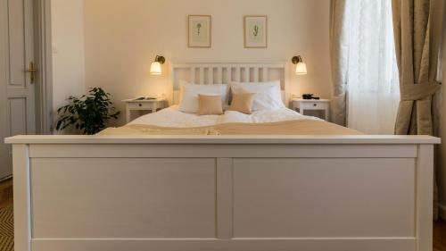 a bedroom with a white bed with two tables at Villa Lenka in Tiszafüred