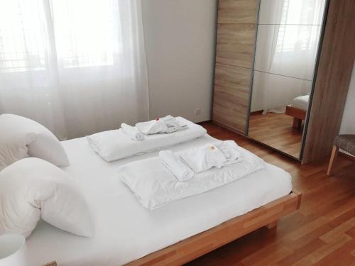 a bedroom with a white bed with a mirror at Easy-Living Apartments Dietwil in Dietwil
