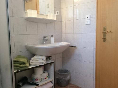 Baño blanco con lavabo y espejo en Gästehaus Wastian en Weissbriach