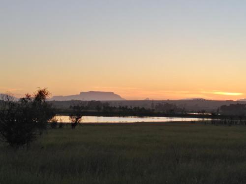 a sunset over a field with a body of water at Wild Clover Cottages in Stellenbosch