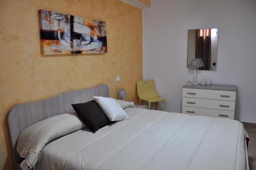 a bedroom with a large white bed and a dresser at House Le Fontanelle in Lizzano