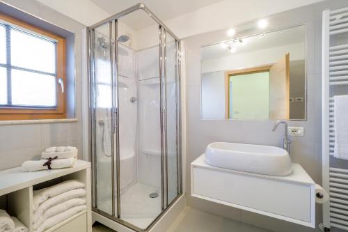 a white bathroom with a shower and a sink at Appartamenti Casa Salesai in Carano