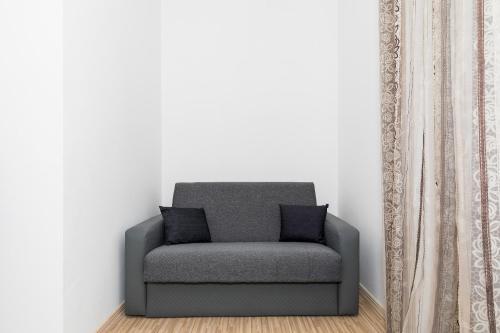 a grey chair sitting in a corner next to a curtain at Krab in Rewal
