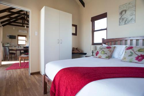 1 dormitorio con 1 cama grande con manta roja en Wild Clover Cottages, en Stellenbosch