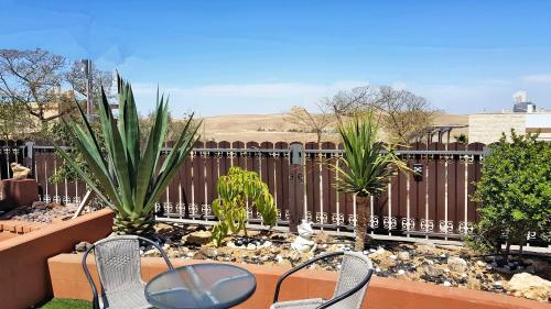 a patio with chairs and plants on a fence at Dead Sea Sun Guest House in Arad