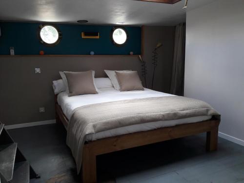 a bedroom with a large bed with two windows at Péniche La Belle Aimée in Aigues-Mortes