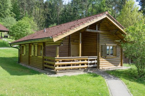 a log cabin with a porch and a grass yard at Blockhäuser Stamsried in Stamsried