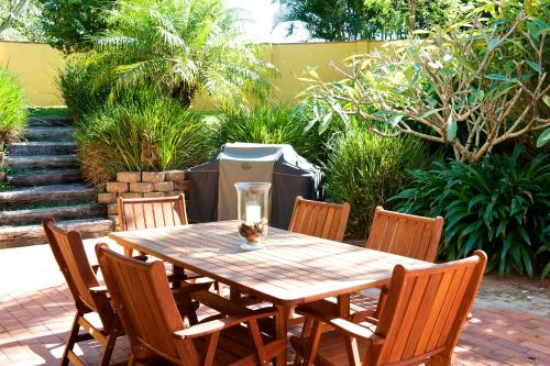 a wooden table and chairs in a garden at Byron Links Apartments in Byron Bay