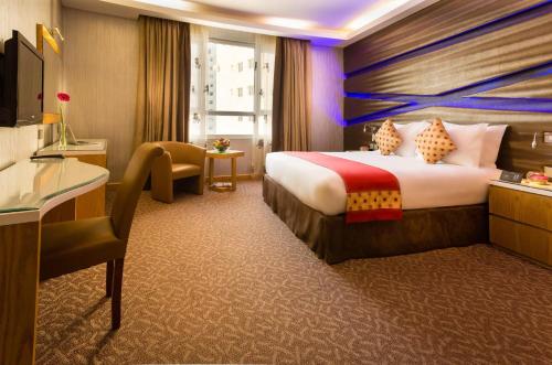 Al Safir Hotel في المنامة: غرفة فندقية بسرير كبير وكرسي