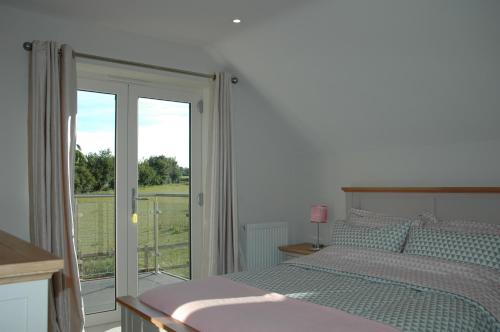 Schlafzimmer mit einem Bett und einer Glasschiebetür in der Unterkunft The Winning Post, Bruton in Bruton