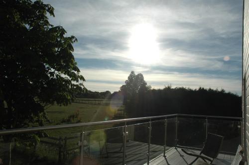 a balcony with a view of a field and the sun at The Winning Post, Bruton in Bruton