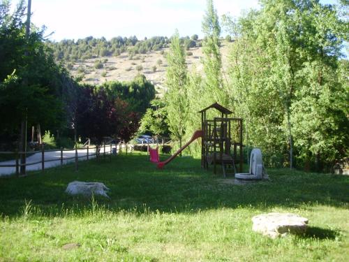 a playground with a slide in the grass at Casa los Tres Nogales in Castroserna de Arriba